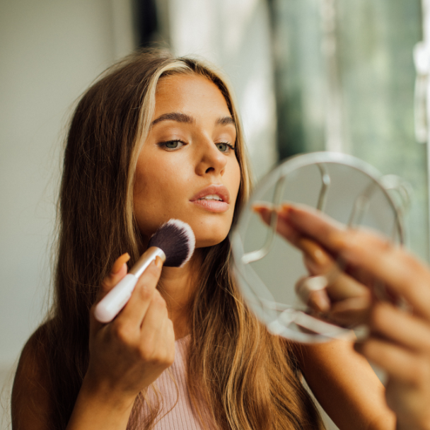 Junge Frau im Spiegel, die Make-up aufträgt