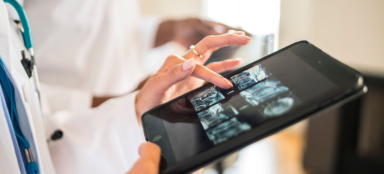 Doctor's in a row working looking at xrays and cat scans with digital tablets.