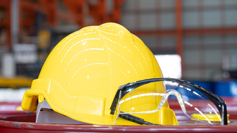 Yellow hard hat with protective glasses in warehouse