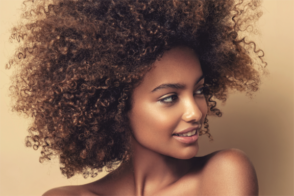 Face, makeup and brush with a woman black model applying foundation to her skin in studio for cosmetics. Portrait, wellness and luxury with an attractive young female using a cosmetic product