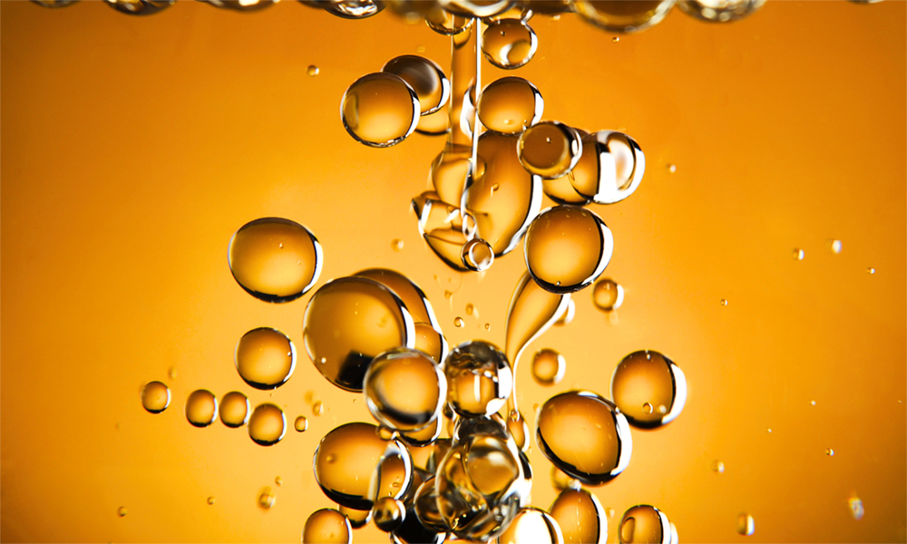 Golden oil droplets suspended in liquid, illustrating Momentive silicone surfactants for improved surface wetting and dispersion in oil and gas applications.