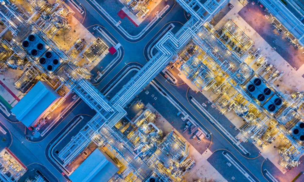 Aerial view of downstream oil and gas processing facility with complex pipelines and equipment for chemical solutions like antifoams and demulsifiers.