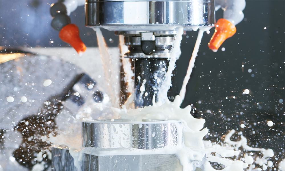 Close-up of CNC machining process with white lubricant spray, representing Momentive’s Alkyl and Aryl silicone fluids and PDMS lubricants for superior thermal stability and wear protection.