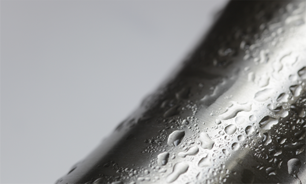 Close-up of metal surface with water droplets, representing Momentive’s mold release auxiliary processing aids for improved coverage and enhanced surface finish.