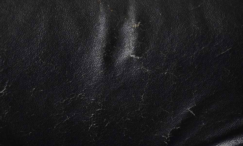 Close-up of a scratched black leather surface, showing damage that can occur without the use of Indusil™ silicone emulsions to improve abrasion and scratch resistance.