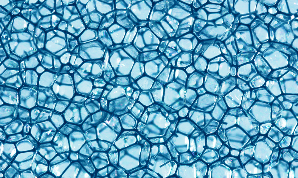 Close-up of blue foam cells illustrating process and foam modifiers for improved adhesion and load-bearing in polyurethane applications.