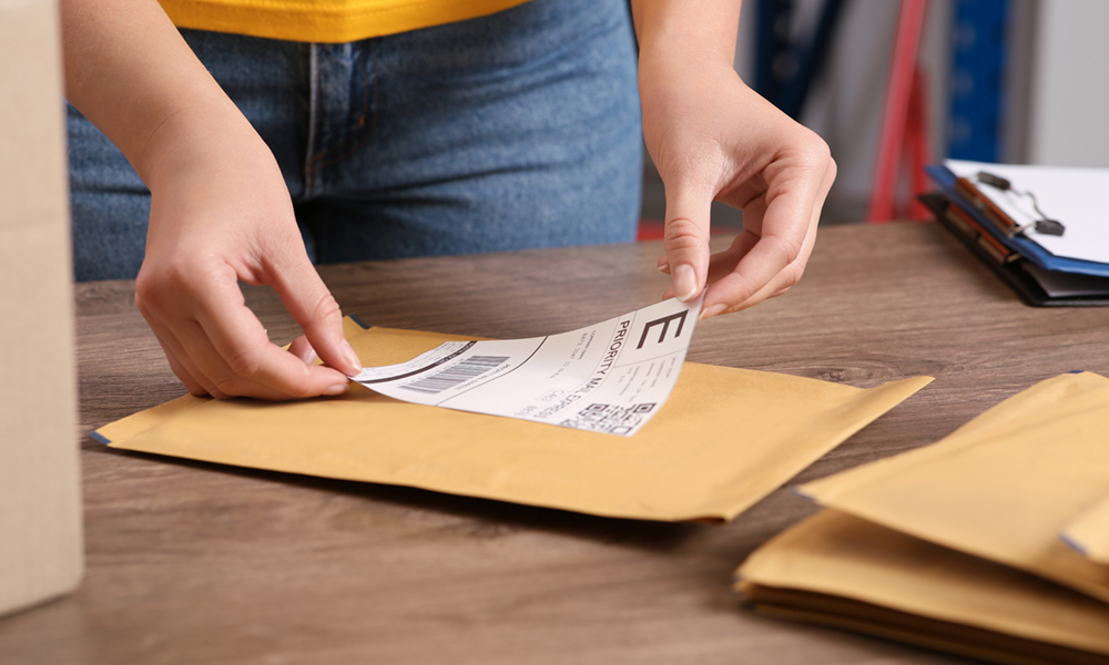 Woman placing a shipping label on envelope