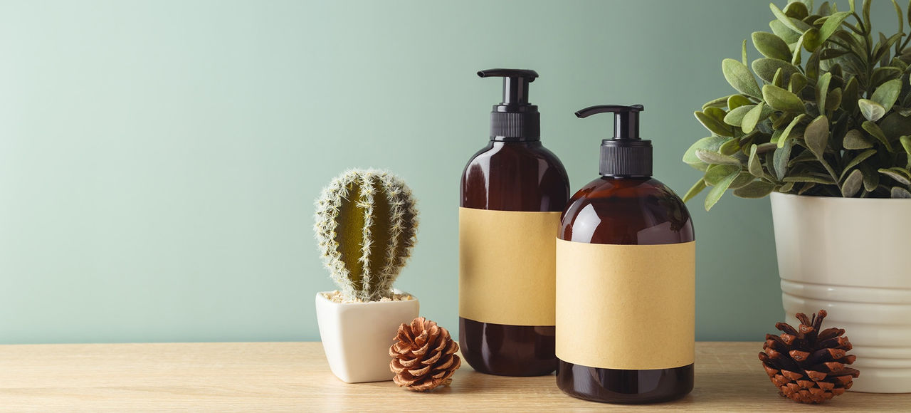 Natural beauty SPA cosmetics bottles with labels for mock up packaging design on wooden table over green background.
