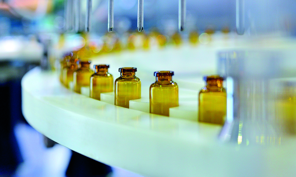Close-up of brown glass bottle filling at production line