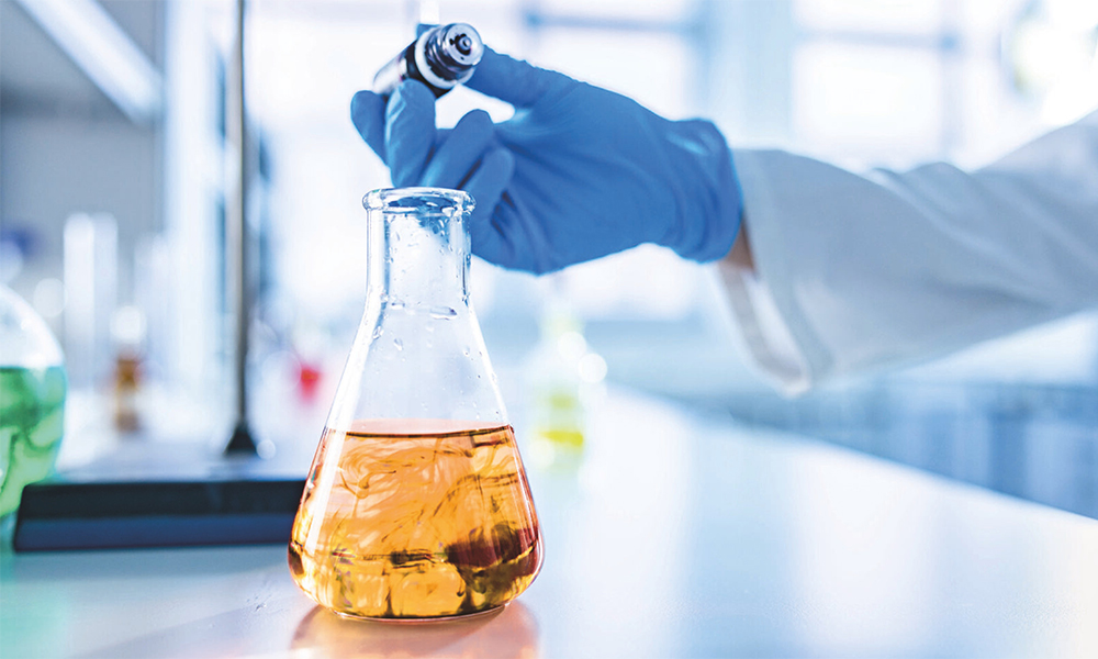 Experimento de laboratório com solução âmbar em frasco demonstrando os catalisadores da Momentive para reações eficientes de espuma de poliuretano.